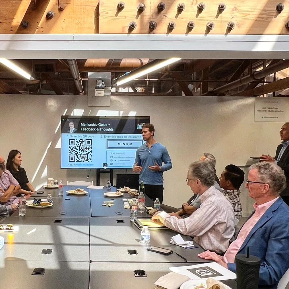 speaker presenting mentorship guide to business professionals during a leadership session.