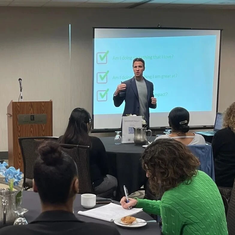 speaker delivering a leadership presentation to professionals at a workshop.